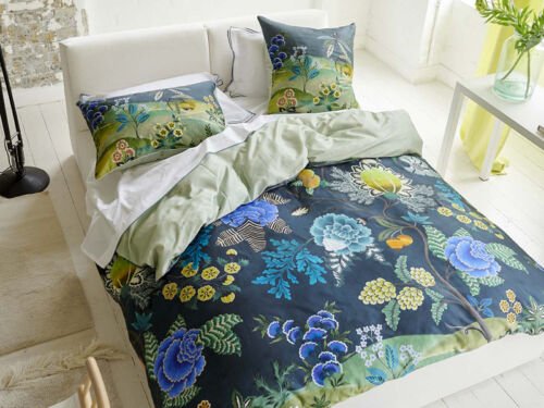Blaue Bettwäsche mit bunten Blumen und grüner Hügellandschaft