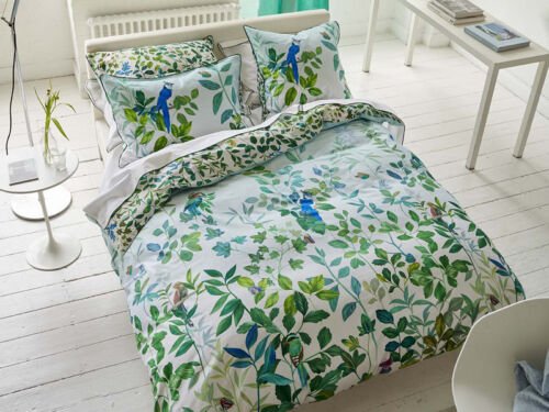 Weißer Raum mit weißem Bett und fröhlicher Sommerbettwäsche in Blau und Grün